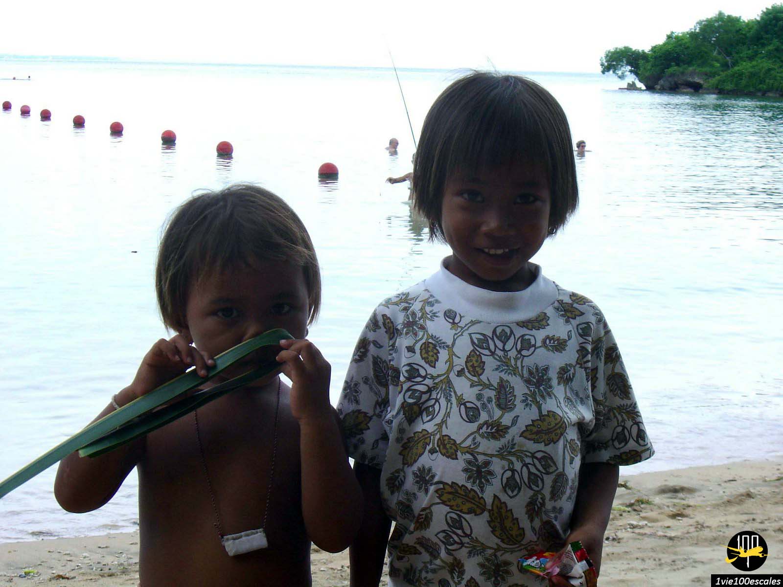 Des enfants avec le sourire se promenant et pris en photo sur la plage publique de Nusa Dua à Bali