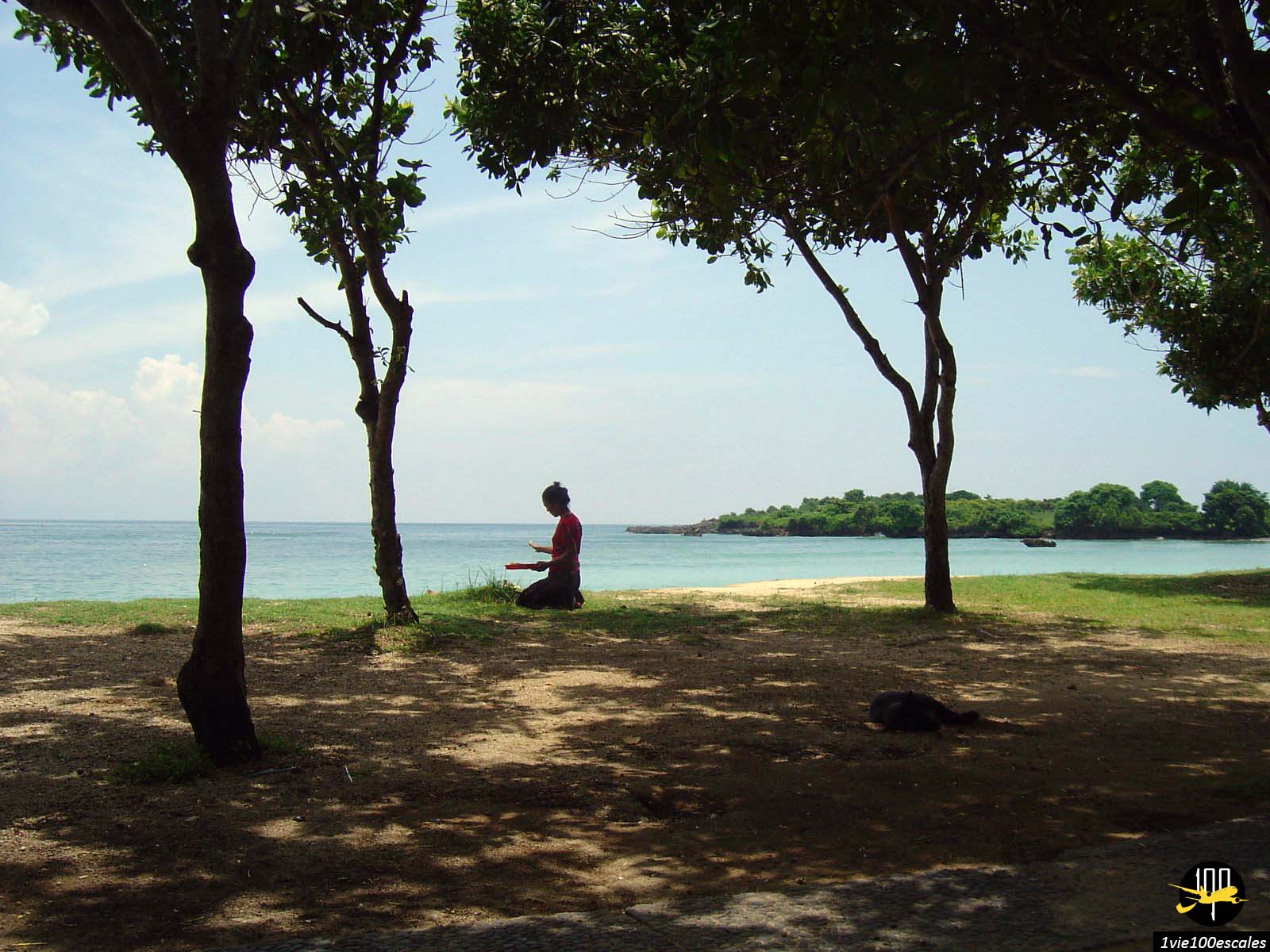 Une femme qui fait la prière à genoux sur la plage publique de Nusa Dua de Bali