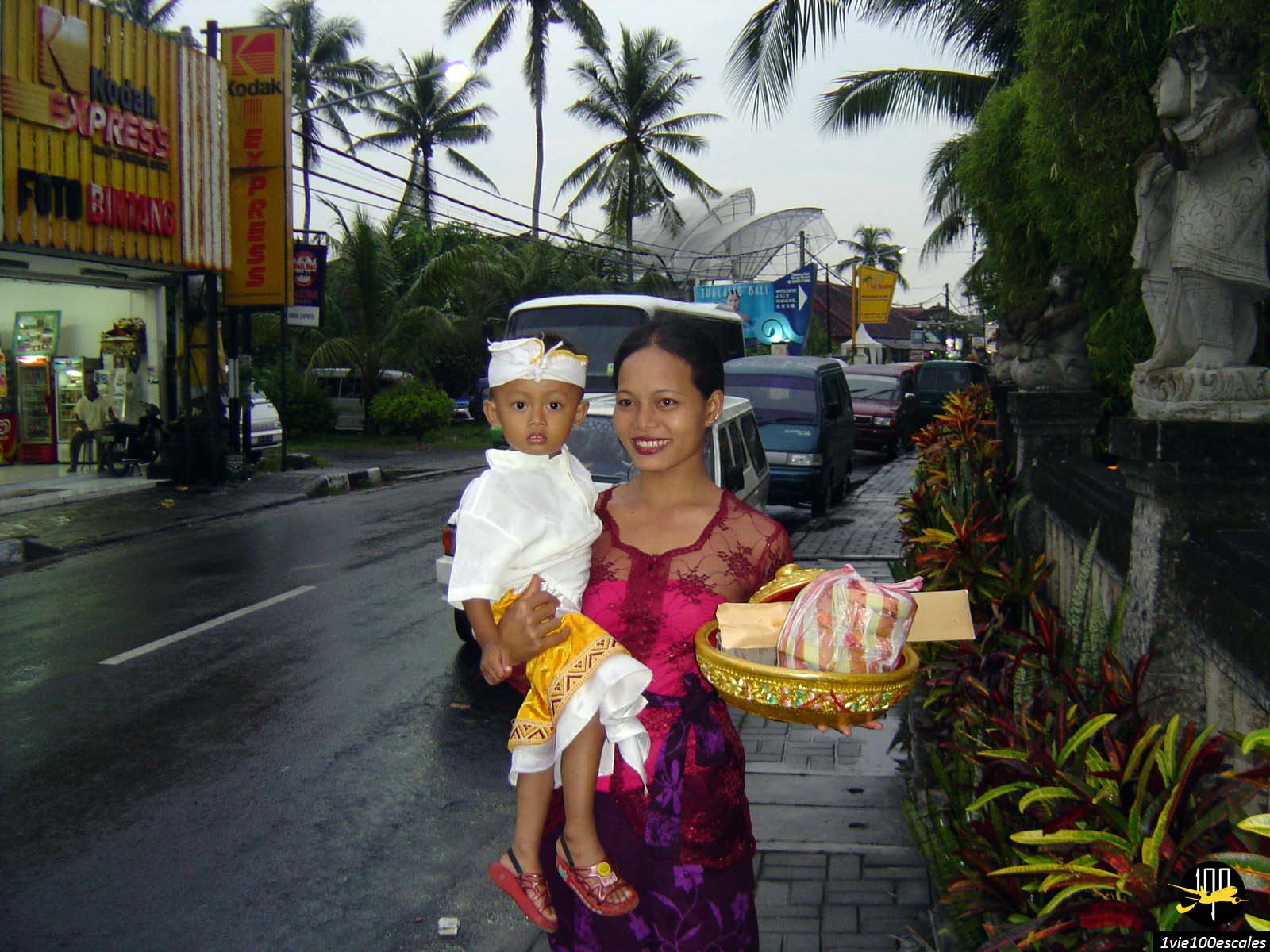 Femme et enfant habillés en costumes traditionnelles religieux avec des offrandes dans les rues de Bali