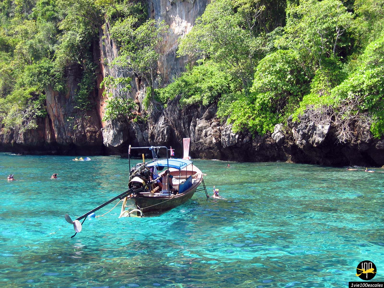 Un bateau à longue queue amarré dans la mer turquoise de la Baie de Phang Nga