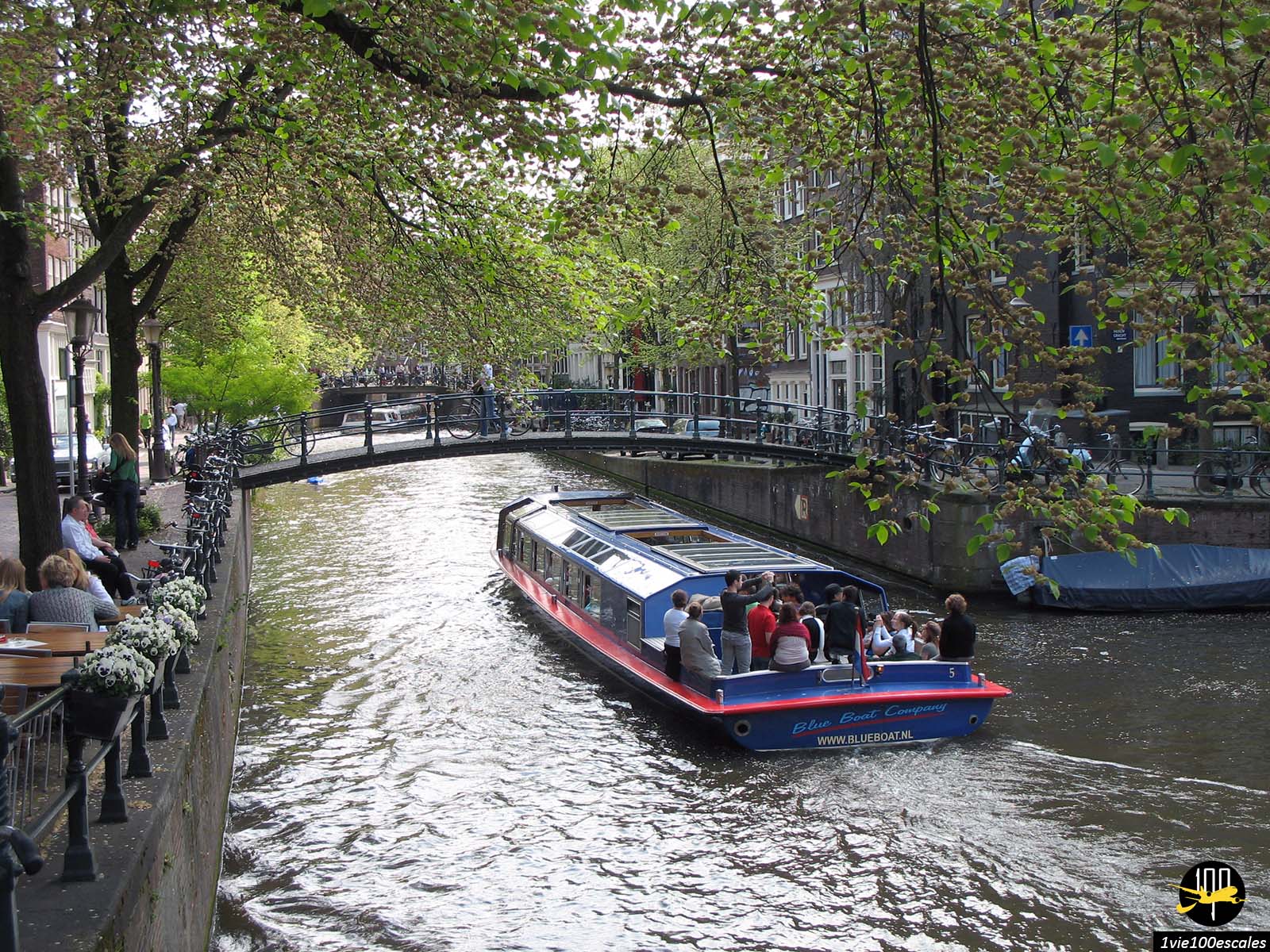 Les touristes en bateaux sur un canal à Amsterdam passant sous un pont