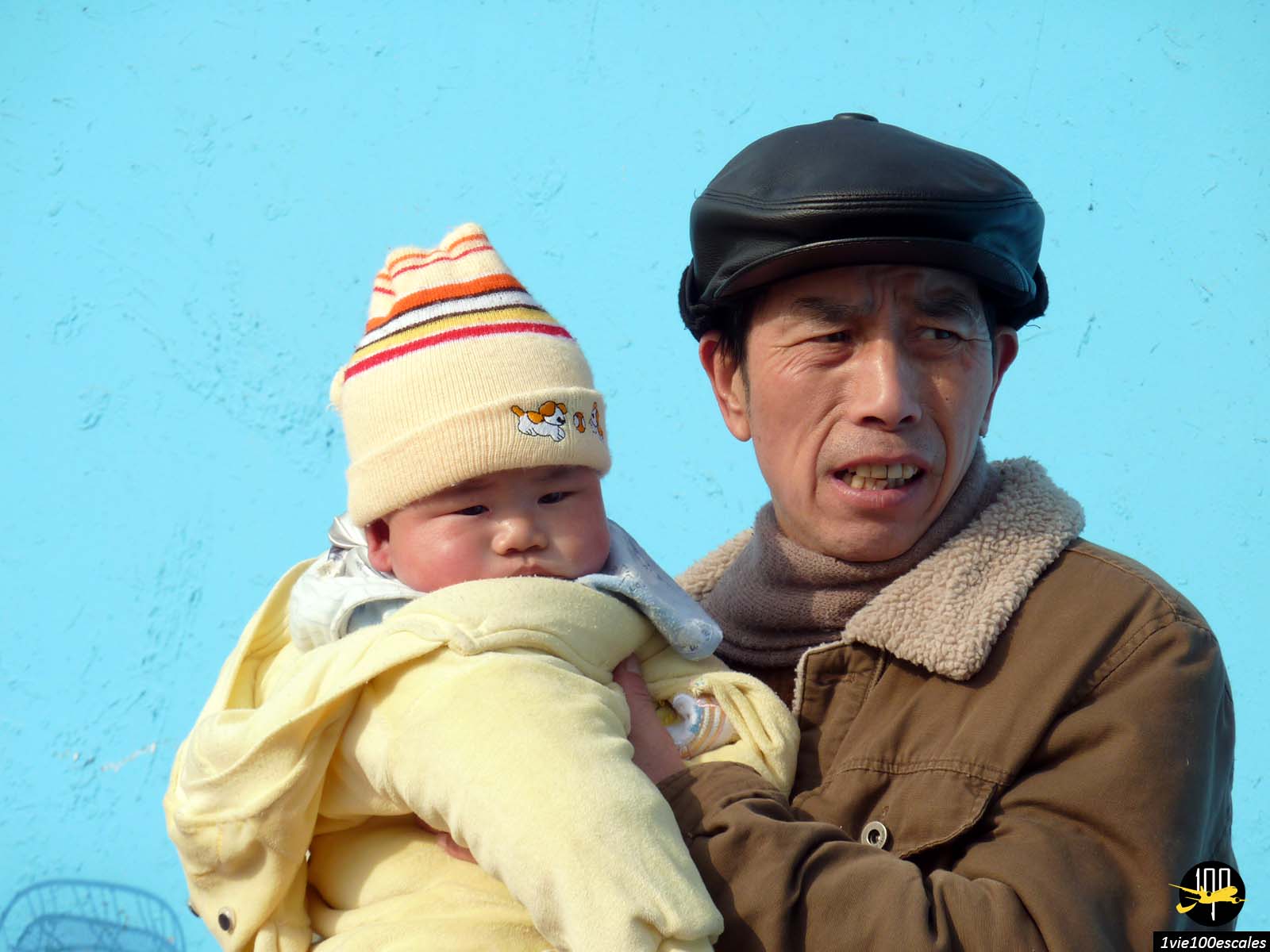 Portait d'un homme chinois avec un enfant dans ses bras dans une rue de Shanghai