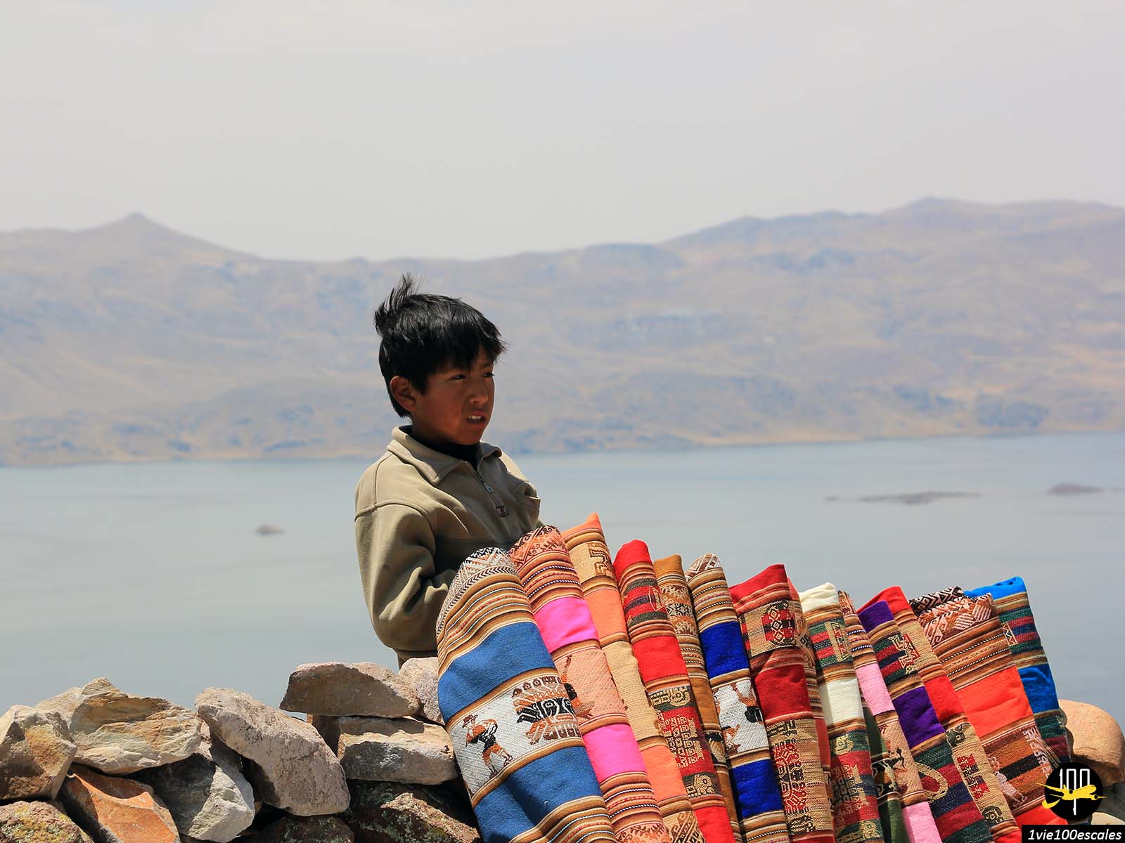 Un enfant péruvien vendant des écharpes aux touristes au bird du lac dans la Réserve nationale Salinas y Aguada Blanca