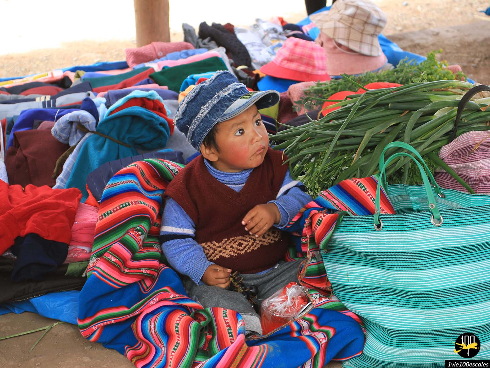 Un mignon petit enfant péruvien assis dans un stand du marché de Chinchero au Pérou