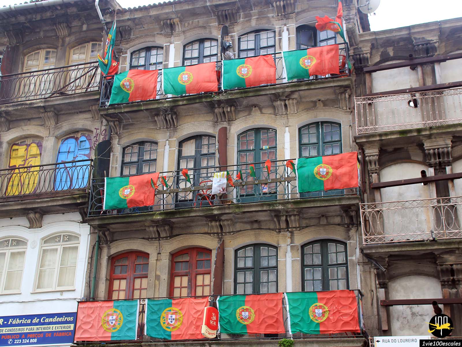 De nombreux drapeaux portugais accrochés sur des balcons d'un vieil immeuble à côté de la gare de Porto
