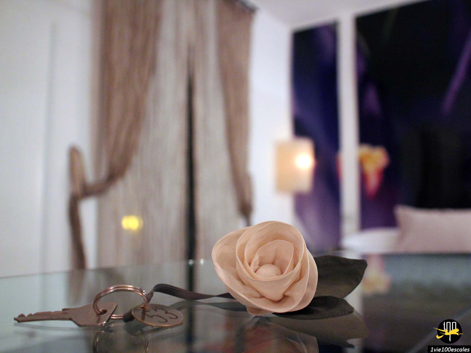 Une clé et une rose sur une table en verre.