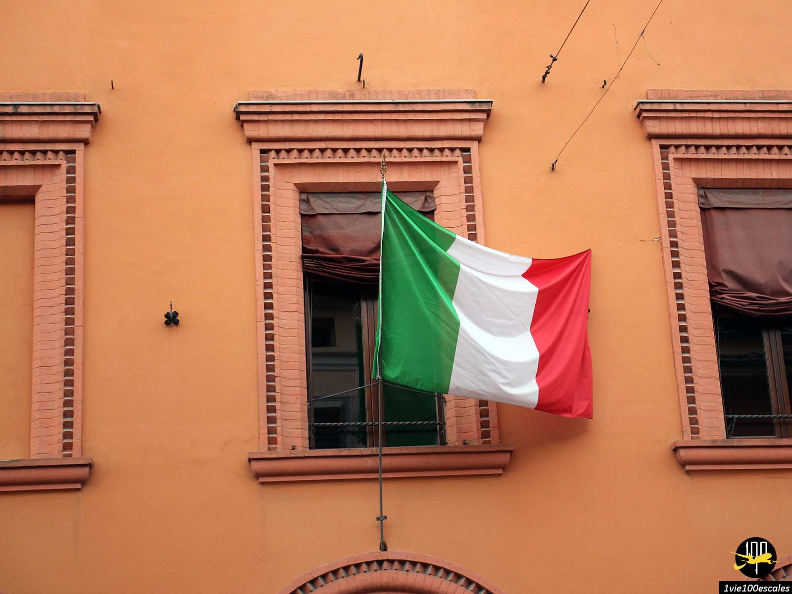 Un drapeau italien flotte sur le côté d’un immeuble.
