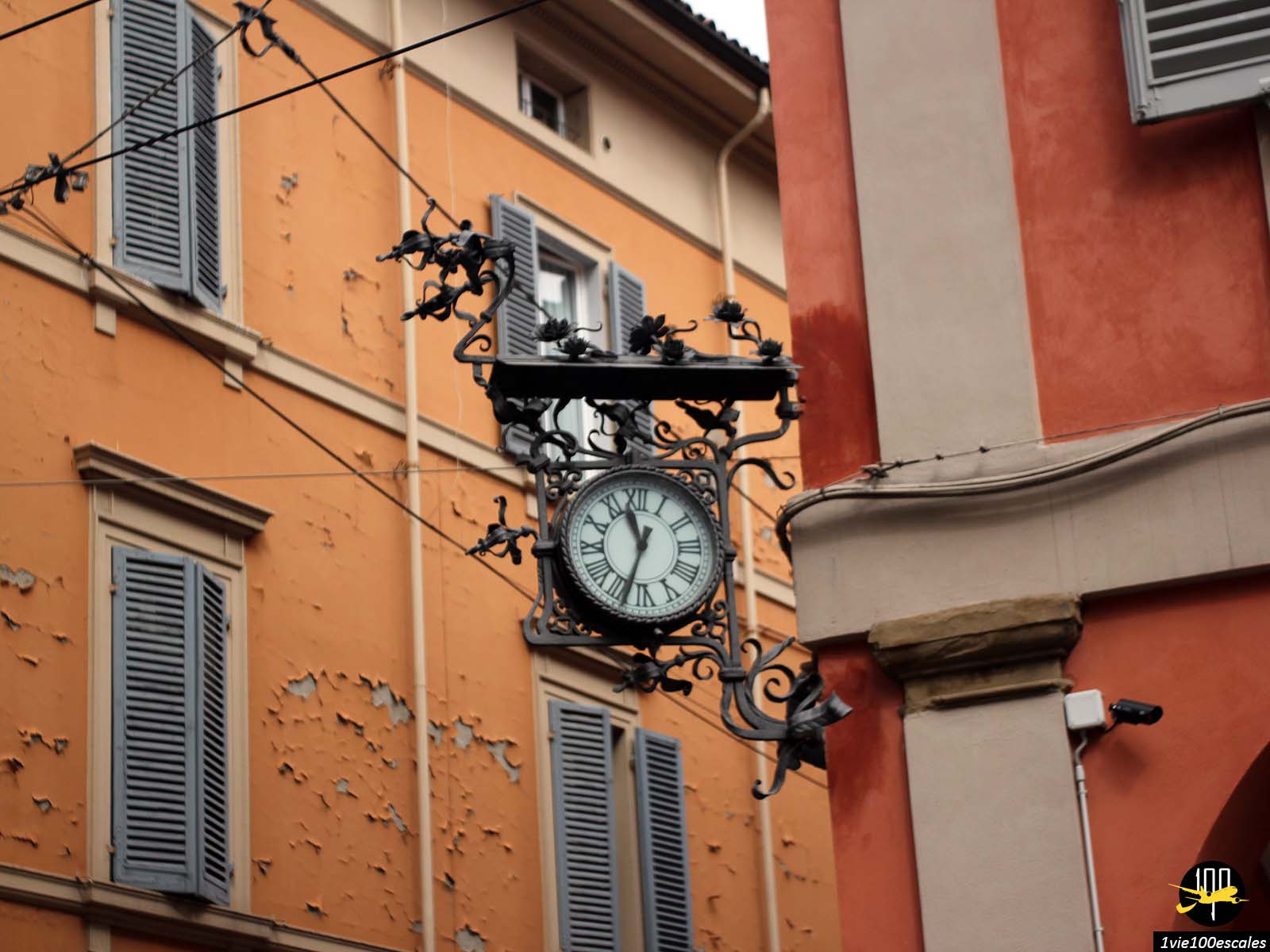 Une horloge accrochée au côté d’un immeuble.
