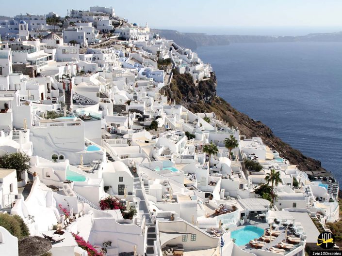 Des bâtiments blanchis à la chaux avec des accents bleus et des piscines ornent la falaise surplombant la mer à Santorin en Grèce.