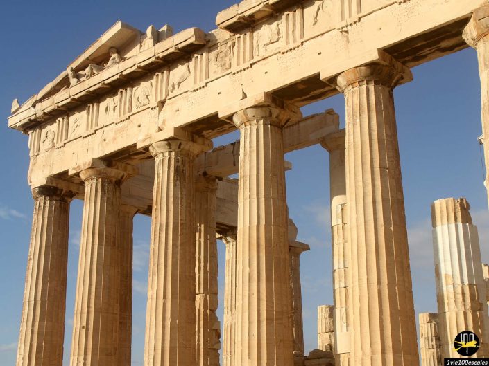 Vue rapprochée des colonnes et de la structure de l'ancien Parthénon à Athènes en Grèce, mettant en valeur ses détails architecturaux classiques sur un ciel clair.