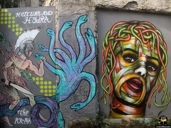 Graffiti représentant Hercule combattant l'Hydre à gauche et une figure colorée ressemblant à une Méduse aux cheveux de serpent à droite, peints sur un mur de béton patiné à Athènes en Grèce.