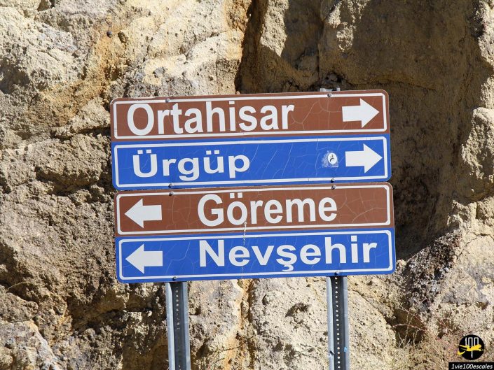 Panneaux routiers directionnels indiquant Ortahisar et Ürgüp à gauche, Göreme tout droit et Nevşehir à droite, sur fond rocheux en Cappadoce en Turquie.