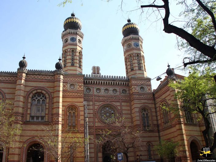 Vue extérieure avant de la synagogue de la rue Dohány à Budapest en Hongrie, présentant son architecture néo-mauresque distinctive avec deux grandes tours en forme de dôme et une maçonnerie complexe.