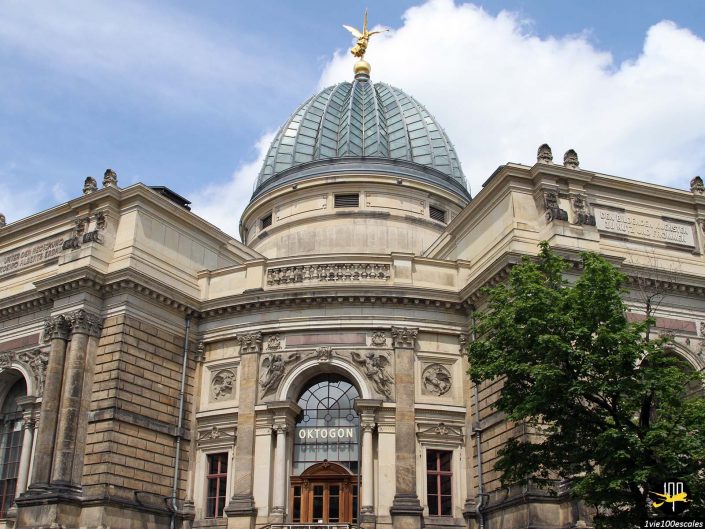 Un bâtiment néoclassique doté d'un grand dôme surmonté d'une statue dorée, situé à Dresde en Allemagne. Le bâtiment présente des colonnes et des pierres ornées, avec un panneau indiquant « OKTOGON » au-dessus de l'entrée.